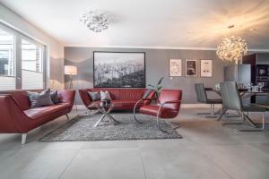 a living room with a red couch and chairs at - DESIGN & STYLE - Modern House with terrace & garden in Wesel