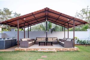 a pavilion with chairs and a table on a patio at Casa Serenity by StayVista - Relax with a pool, lawn, and inviting jacuzzi in Lonavala