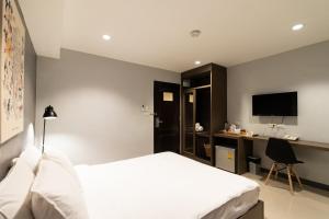 a bedroom with a bed and a desk with a television at North Inn Town Chiangmai in Chiang Mai