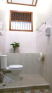 La salle de bains est pourvue de toilettes et d'une plante. dans l'établissement Sleepy Raccoon Hostel, à Yogyakarta