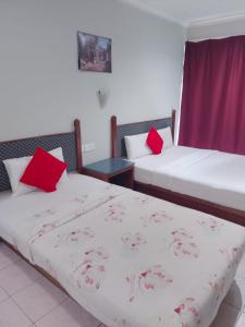 Highway Inn في Mukah: سريرين مع وسائد حمراء في الغرفة