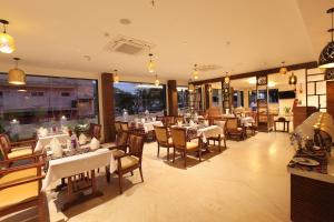 a restaurant with white tables and chairs and windows at HOTEL MARIA PARK in Mūvattupula