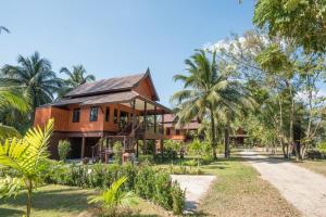 a house with palm trees in front of it at ThaiLife Wellness & Meditation Resort- SHA Plus in Khao Lak