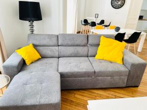 CHIC Appartement Type 4 / Parking Privé في رانس: أريكة رمادية مع وسائد صفراء في غرفة المعيشة