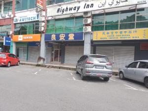 Highway Inn في Mukah: سيارتين متوقفتين في موقف للسيارات امام مبنى