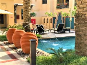 een zwembad met oranje vaten naast een gebouw bij Stunning Apt with Spacious Terrace Old Town Dubai in Dubai