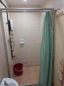 a bathroom with a shower with a toilet and a red bucket at Highway Inn in Mukah