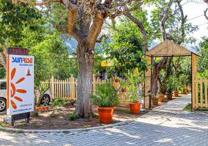 una señal junto a un árbol y una valla con plantas en Sunrise Bungalows, en Cıralı