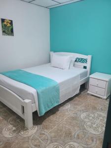 Schlafzimmer mit einem Bett mit blauer Wand in der Unterkunft Vivienda Turistica Cattleya in Filandia