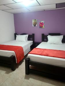 2 Betten in einem Zimmer mit lila und lila Wänden in der Unterkunft Vivienda Turistica Cattleya in Filandia