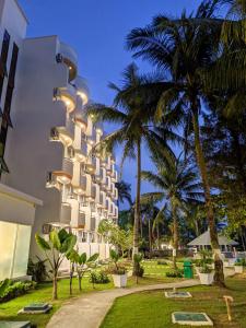 an exterior view of a building with palm trees at HARRIS Resort Batam Waterfront in Sekupang