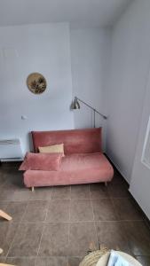 um sofá rosa sentado num quarto em Castèléma - Appartement proche du sanctuaire em Lourdes