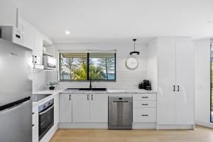 a white kitchen with white cabinets and a window at Beachside Views 2 Bedroom Apartment Mooloolaba in Mooloolaba