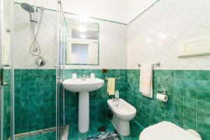 een groene betegelde badkamer met een wastafel en een toilet bij Dimora Bibbò in Salerno