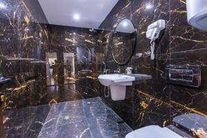 a black marble bathroom with a sink and a mirror at апартаменти Пасажио in Sandanski +41 photos