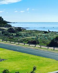 a road next to a field of grass next to the ocean at Stunning Ocean View Villa 2 Dunsborough in Dunsborough