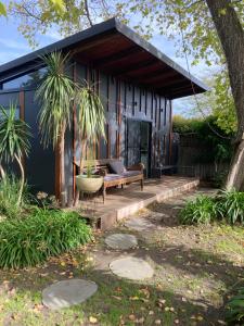 une maison avec un banc sur une terrasse couverte dans l'établissement Bayside Bungalow, à Cheltenham