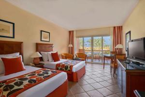 a hotel room with two beds and a flat screen tv at Jaz Grand Marsa in Coraya Bay