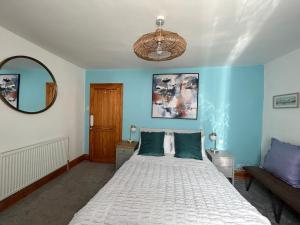 1 dormitorio con cama blanca y pared azul en Fully Equipped Devon 2BR Cottage, en Teignmouth