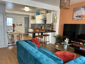 a living room with a blue couch and a kitchen at Fully Equipped Devon 2BR Cottage in Teignmouth