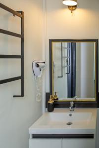 a bathroom with a sink with a mirror and a hair dryer at L'Aparté in Salles