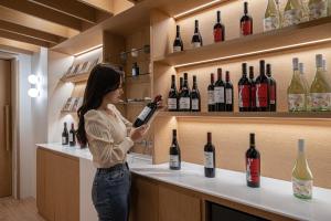 a woman standing at a counter with a bottle of wine at The Hyoosik Aank Hotel Wooam in Cheongju