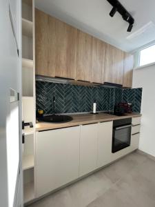 - une cuisine avec des placards blancs et un évier dans l'établissement C & A apartments, à Cluj-Napoca
