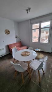 uma sala de estar com uma mesa e cadeiras e um sofá em Castèléma - Appartement proche du sanctuaire em Lourdes