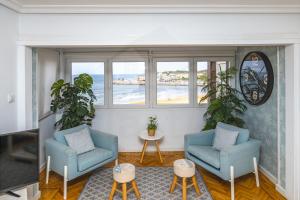 a living room with two chairs and a view of the ocean at Playa Apartamento Frente al mar in Gijón