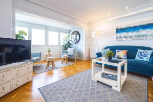 sala de estar con sofá azul y TV en Playa Apartamento Frente al mar en Gijón