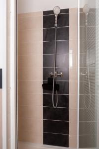 a shower with a glass door and black tiles at L'Aparté in Salles