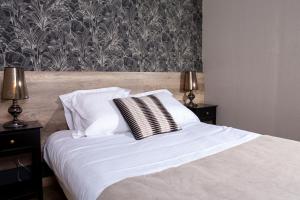 Una cama con sábanas blancas y almohadas en un dormitorio en L'Aparté en Salles