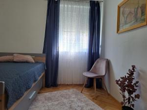 a bedroom with a bed and a window with a chair at Apartment Rita in Dramalj