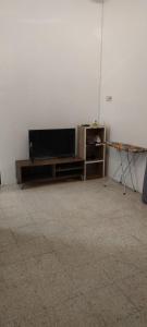 NTC Homestay at Parit Buntar في باريت بونتار: غرفة معيشة مع تلفزيون بشاشة مسطحة وطاولة