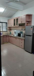 eine Küche mit rosa Schränken und einem Kühlschrank in der Unterkunft NTC Homestay at Parit Buntar in Parit Buntar