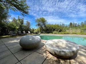 a swimming pool with two stone seats next to a pool at Ndlovu Addo River Lodge in Kirkwood