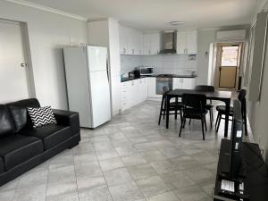a kitchen and dining room with a black couch and a table at Beachside & Jetty View Apartment 7 - Sea Eagle Nest Apartment in Streaky Bay