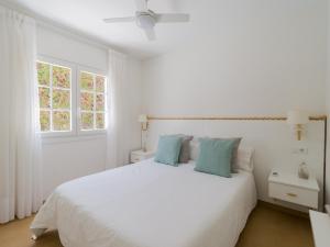 a white bedroom with a white bed with blue pillows at Bungalow Tunos Maspalomas in San Bartolomé