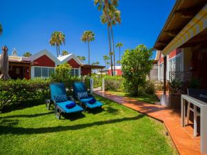 a yard with two blue chairs and palm trees at Bungalow Tunos Maspalomas in San Bartolomé