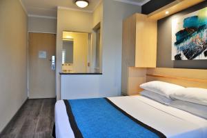 um quarto com uma cama e um quadro na parede em Road Lodge Randburg em Joanesburgo