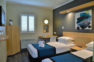 um quarto com duas camas e uma mesa com um bicho de peluche em Road Lodge Randburg em Joanesburgo