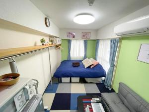 een kleine kamer met een bed en een bank bij Kameari 1111 Budget Stay High Floor Near Station Mall Disney Access in Tokyo