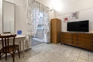 uma sala de estar com uma televisão e uma secretária com uma secretária em Chiarina rooms em Polignano a Mare