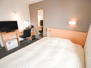 een slaapkamer met een bed en een bureau met een televisie bij Super Hotel Kokuraeki Minamiguchi in Kitakyushu