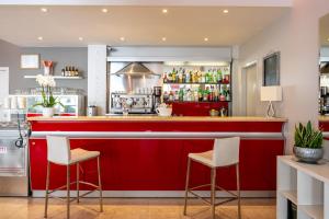 a red bar in a restaurant with two stools at Hotel Doria in Cavi di Lavagna