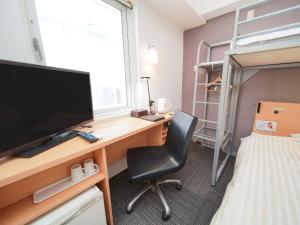 a bedroom with a desk with a computer and a bed at Super Hotel Kokuraeki Minamiguchi in Kitakyushu