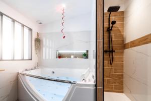 a bathroom with a tub and a shower with a mirror at Love Loft Spa in Ambronay +6 photos