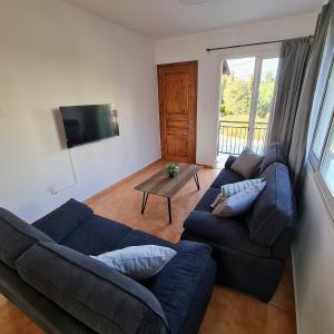 Una sala de estar con un sofá azul y una mesa. en NTORAS Holiday Home, en Pafos