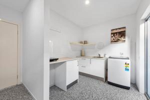 a kitchen with white cabinets and a refrigerator at Scarborough Beach Break Holidays - Unit 5 in Scarborough