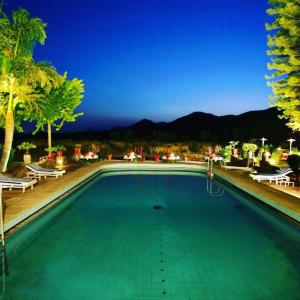 una gran piscina con agua verde y palmeras en Shikarbadi Hotel - Heritage by HRH Group of Hotels, en Udaipur